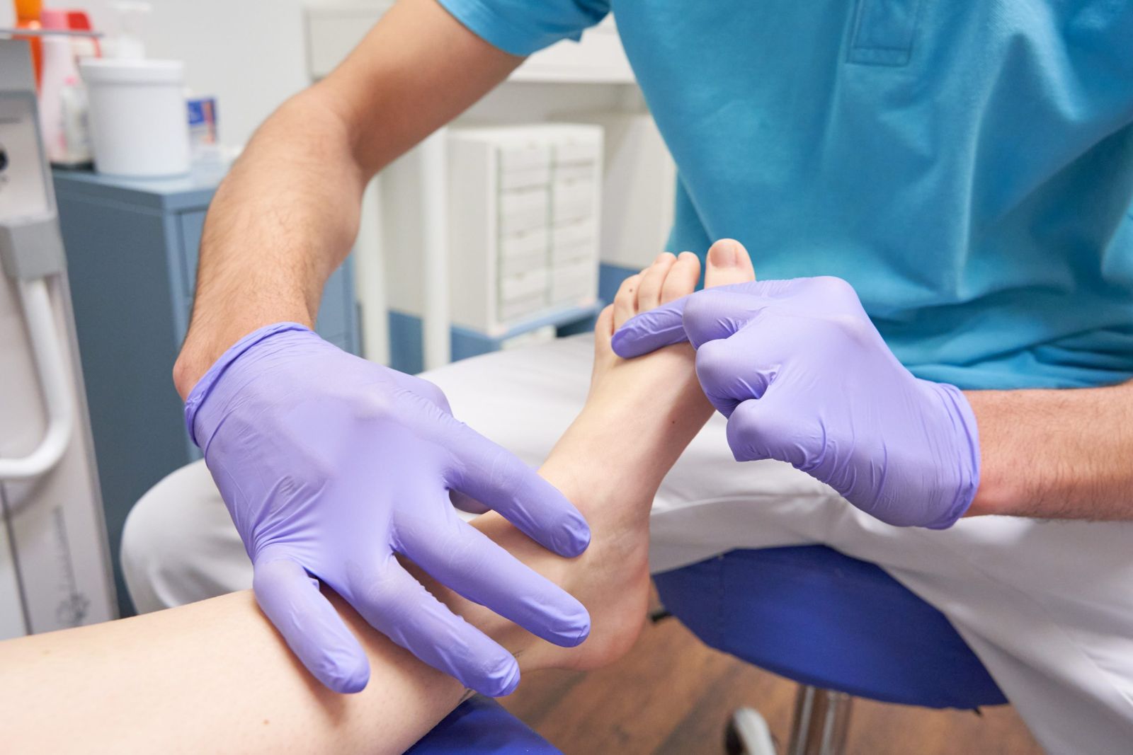 Imagen de profesional con guantes tocando los pies a clienta 
