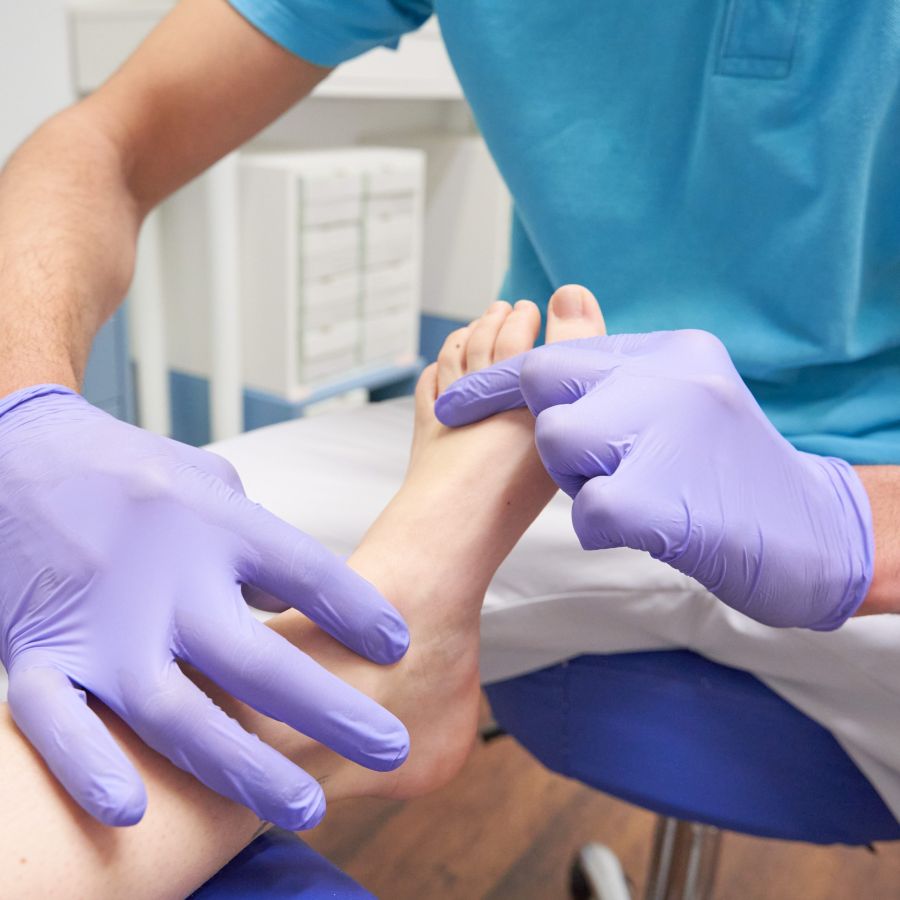 Imagen de profesional con guantes azules tocando pie de clienta 